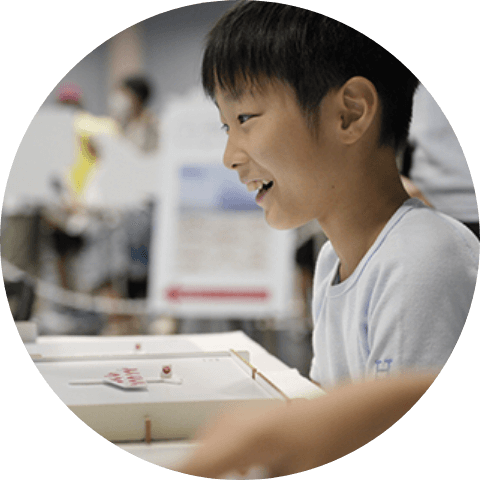 画像：少年が笑顔で展示物を触りながら遊んでいる様子