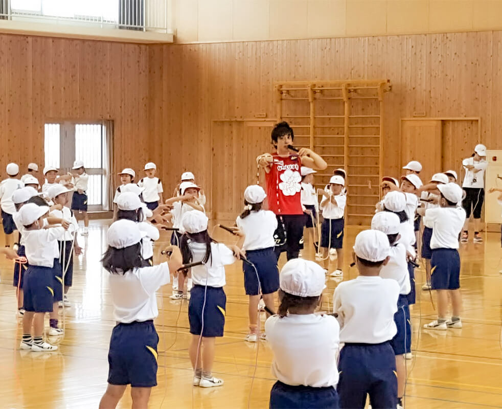 画像：体育館で縄跳びのコツを教えるプロなわとびプレーヤーとこどもたちの様子