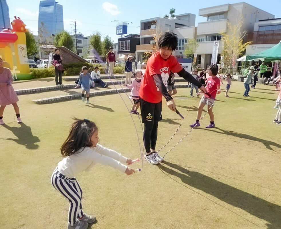 画像：プロなわとびプレーヤーとともに外で縄跳びを楽しんでいる子どもたちの様子