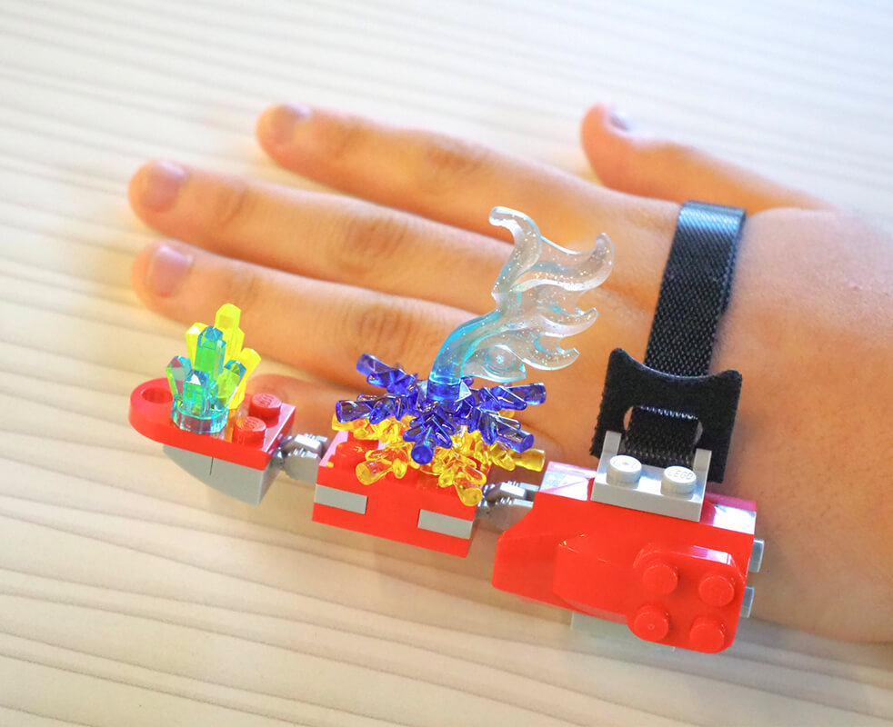 画像：LEGOブロックによって作られた第６の指の機械がこどもの手に装着されている様子
