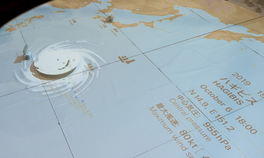 台風の経路を示す大型テーブル型展示物。気圧、最大風速などのデータが表示されている。