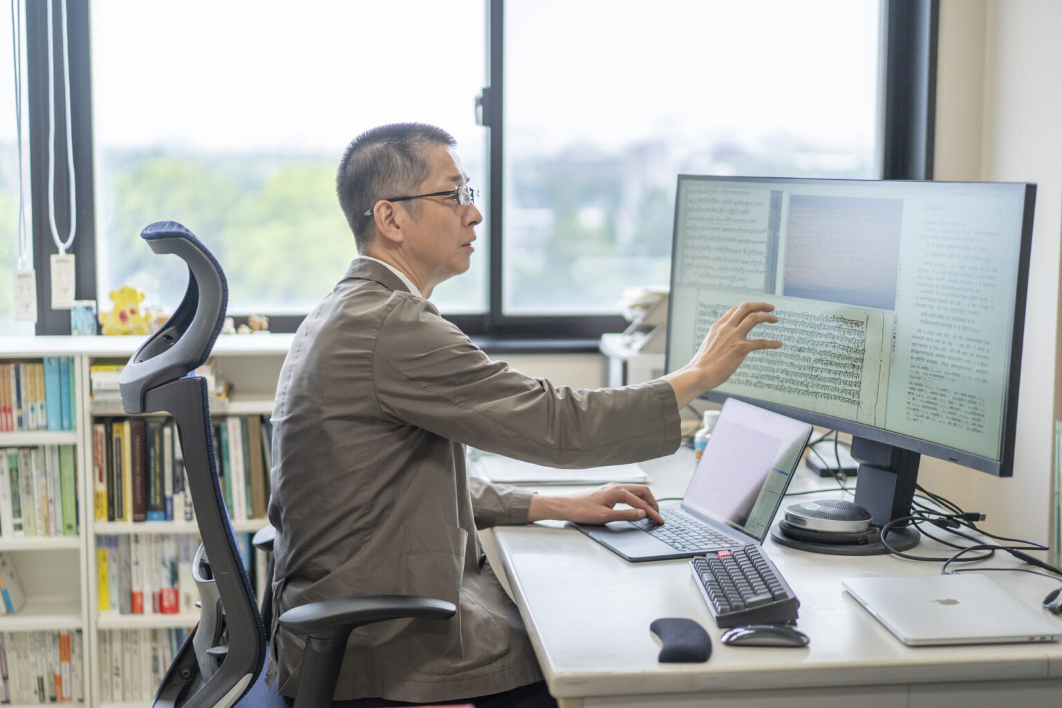 Dr. Shida editing text at his computer